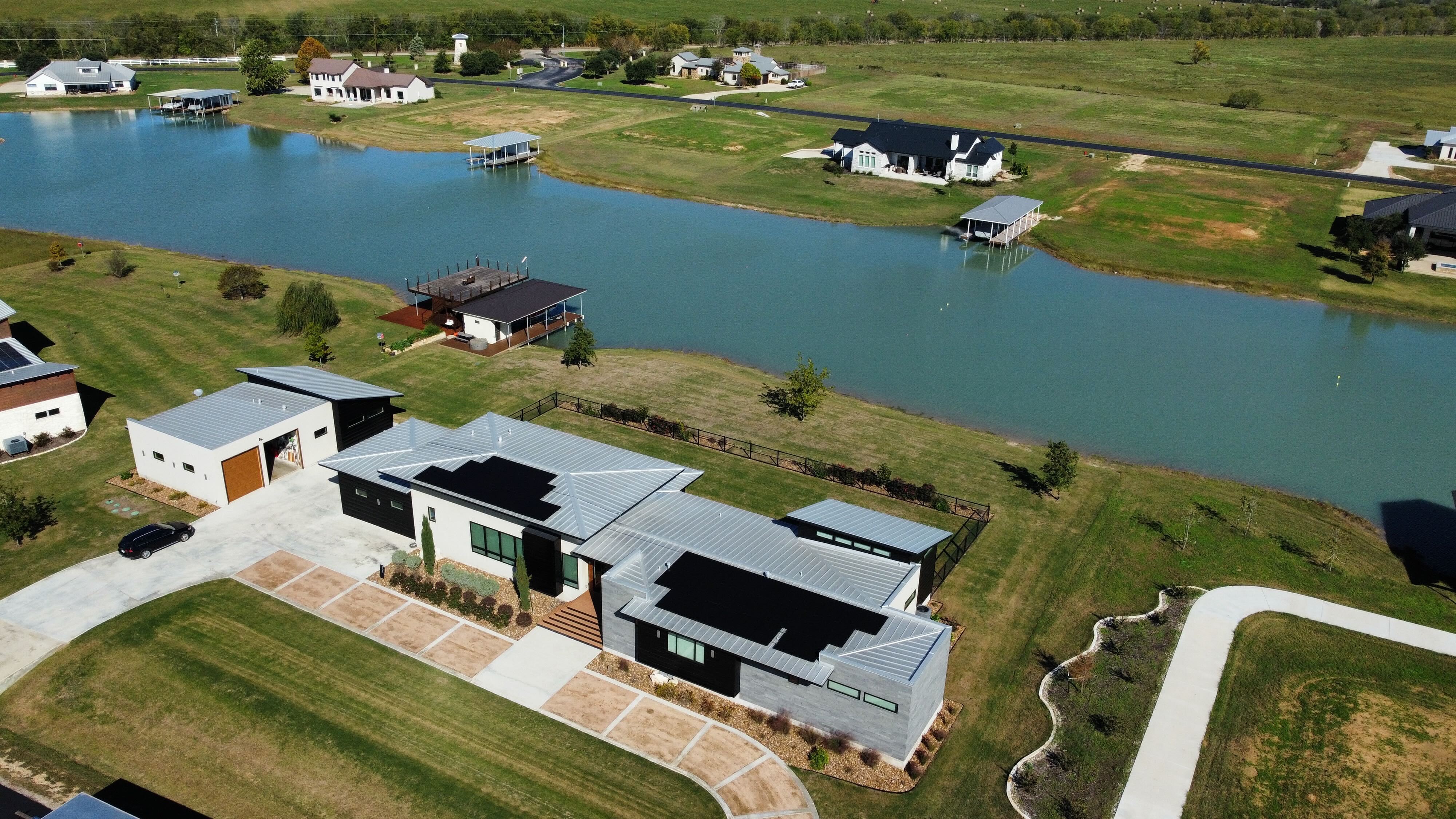 Aerial view of a lakeside Martindale, Texas home with roofio solar and battery backup