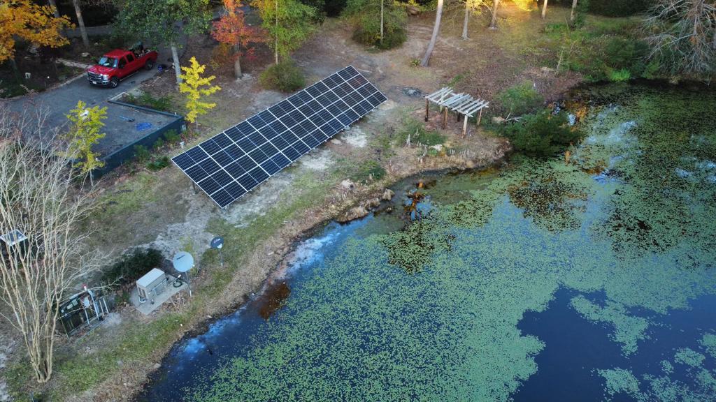 Ground-mounted solar array installed by roofio beside a pond in Woodville, Texas