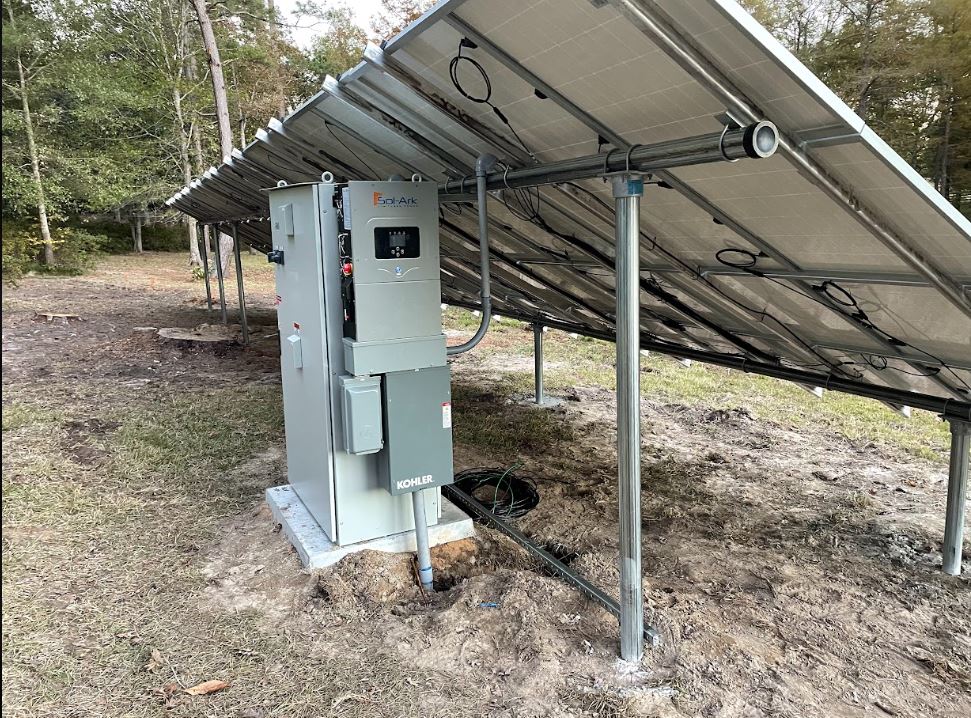 Inverter and disconnect equipment mounted beneath a ground-mount solar array