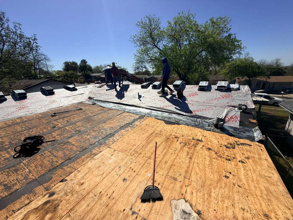 A roofio crew tearing an old roof down to the bare decking on a San Antonio, Texas home