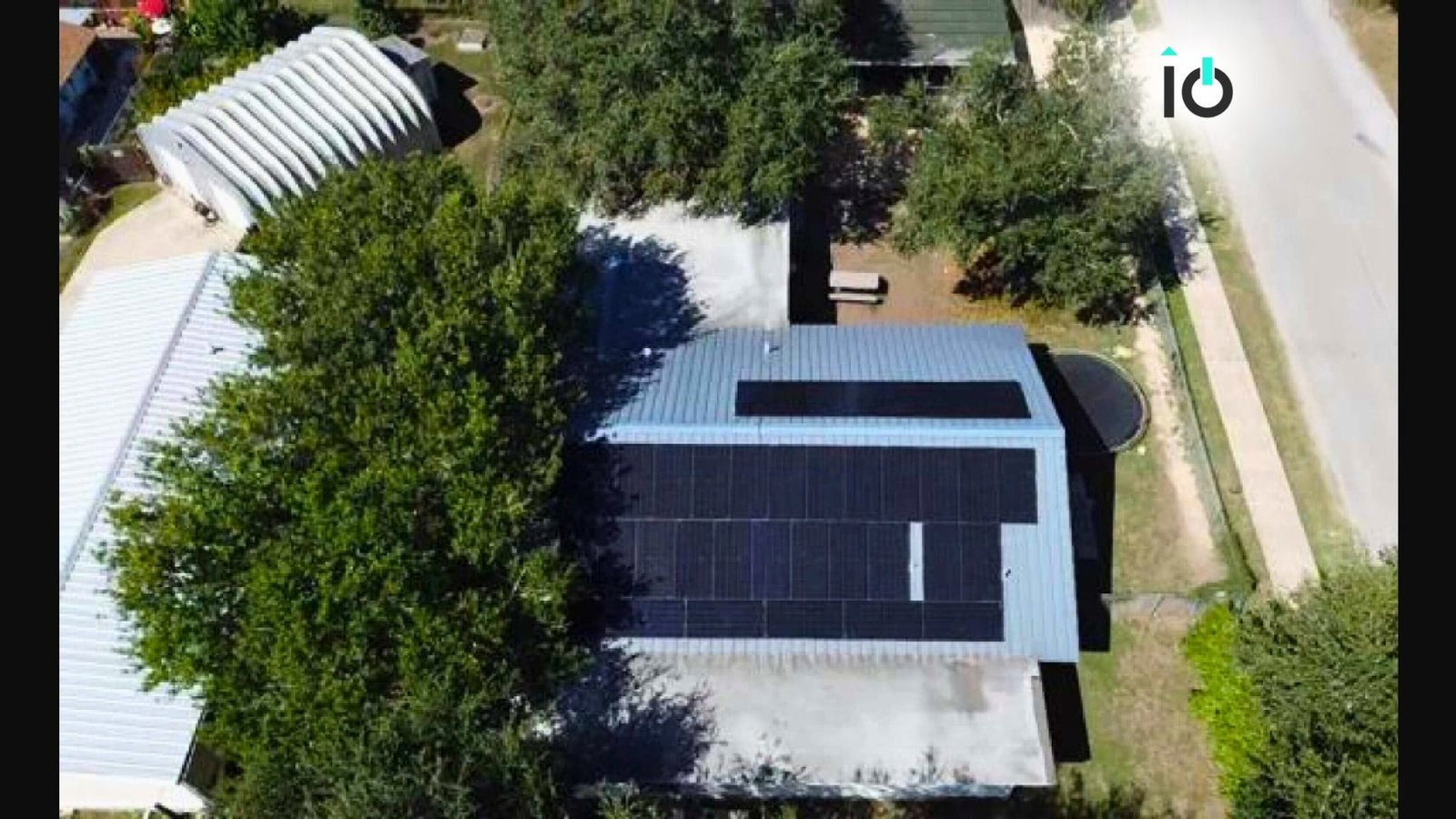 Aerial view of a home with a rooftop solar array surrounded by trees