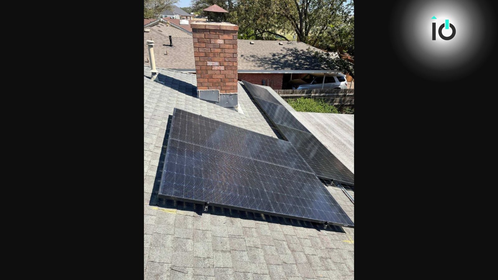 Solar panels beside a brick chimney on a shingle roof
