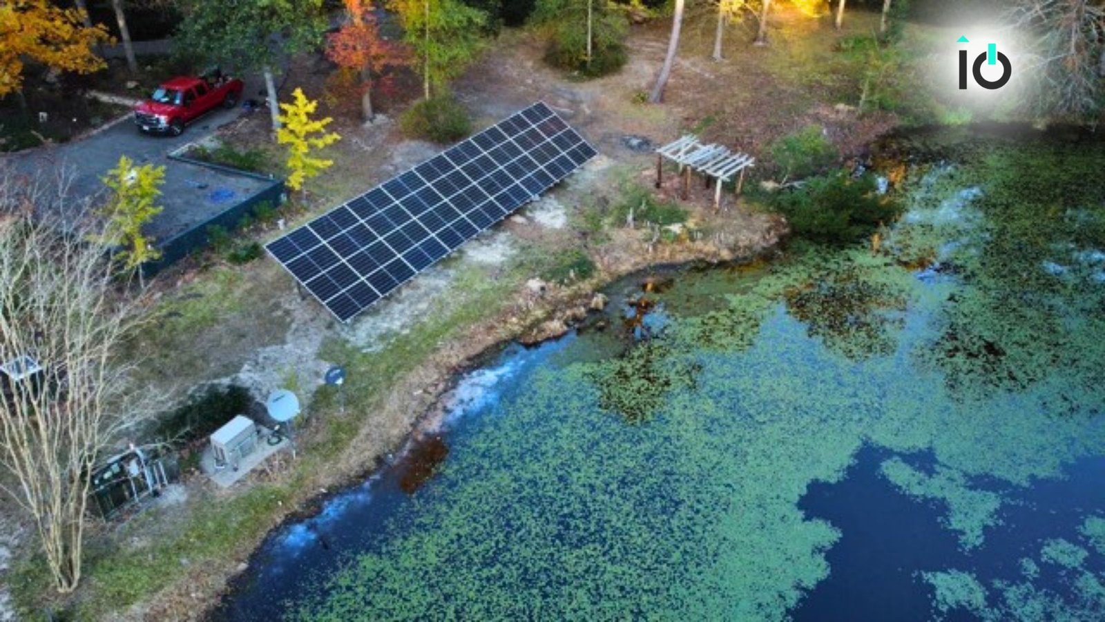 Aerial view of a ground-mounted solar array beside a lake