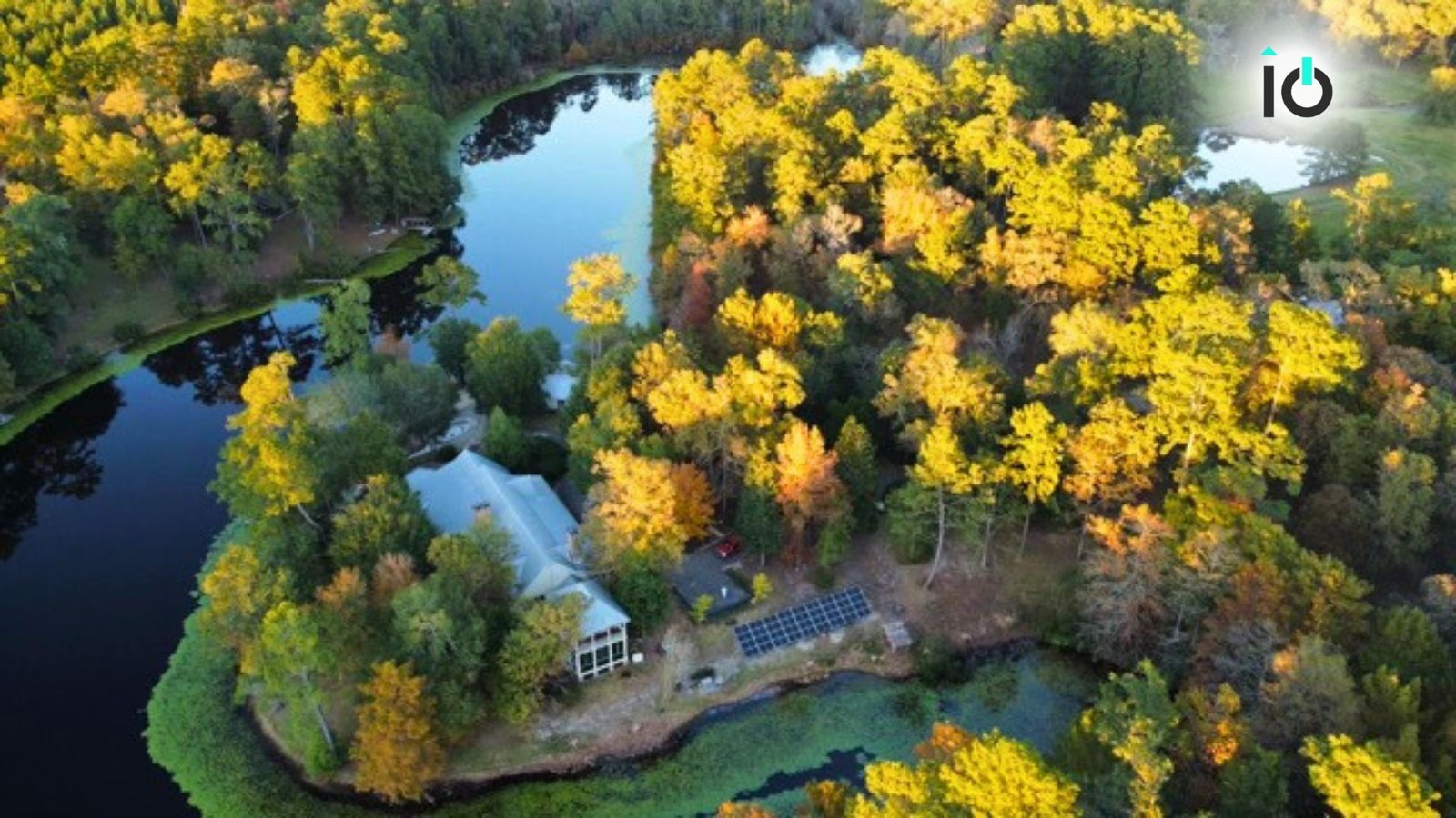 Aerial view of a wooded lakeside property with solar arrays