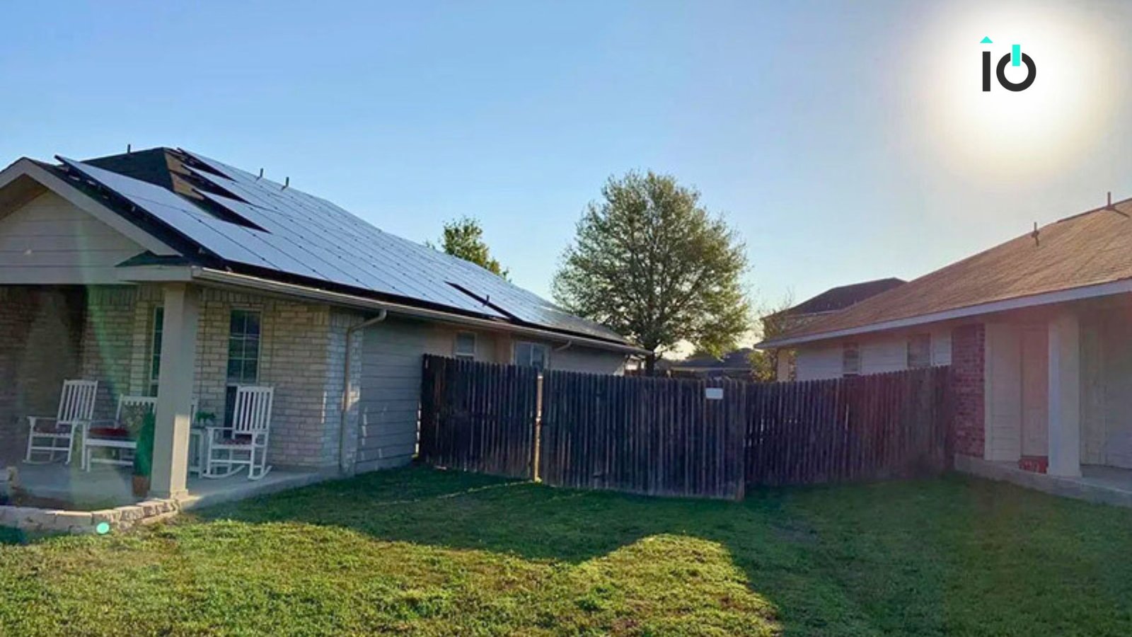 Home with rooftop solar panels behind a backyard fence