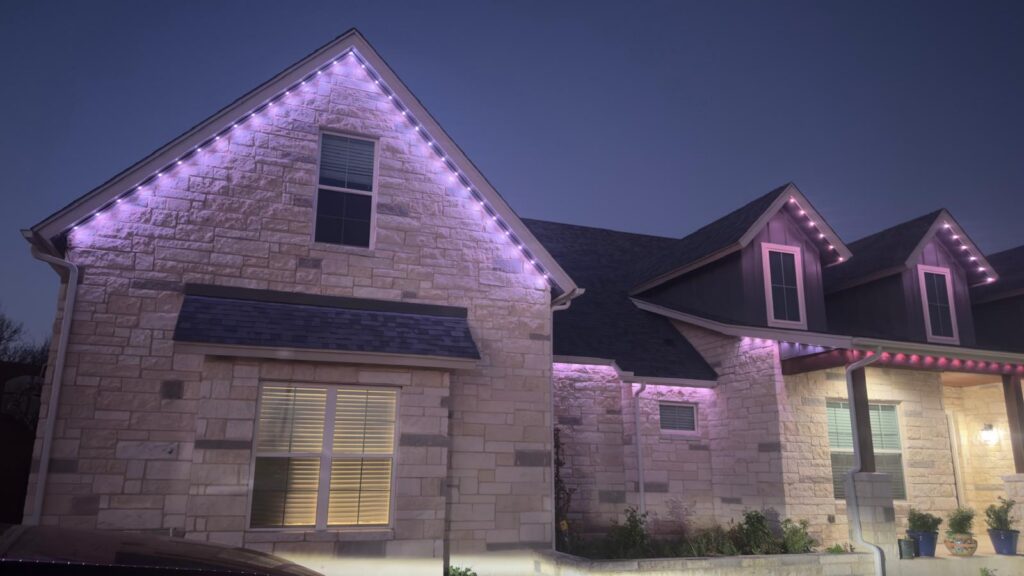 roofio permanent roofline lighting glowing purple across a stone home at night in Helotes, Texas