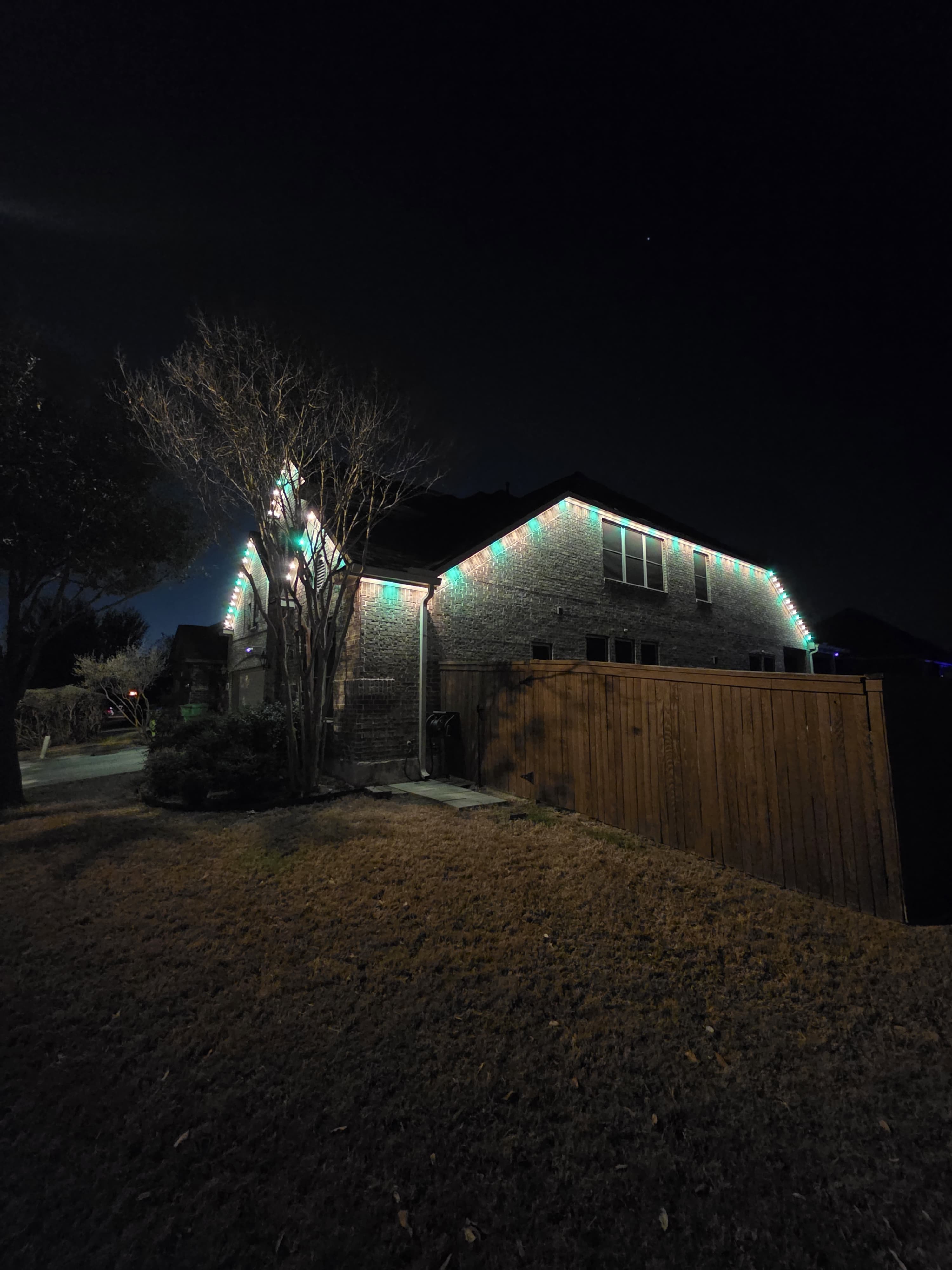 A two-story home with its roofline lit in green and white