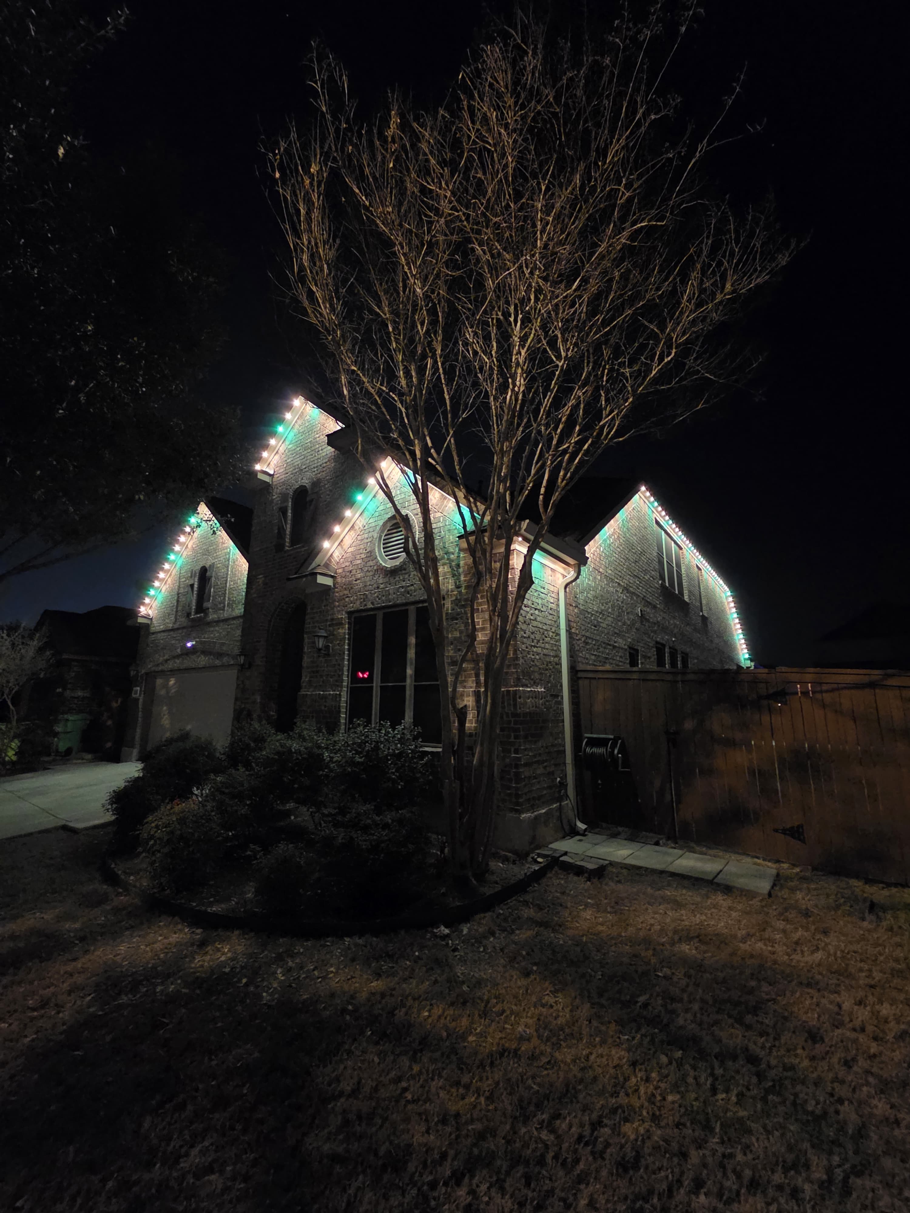 Permanent lighting tracing the rooflines and gables of a home at night