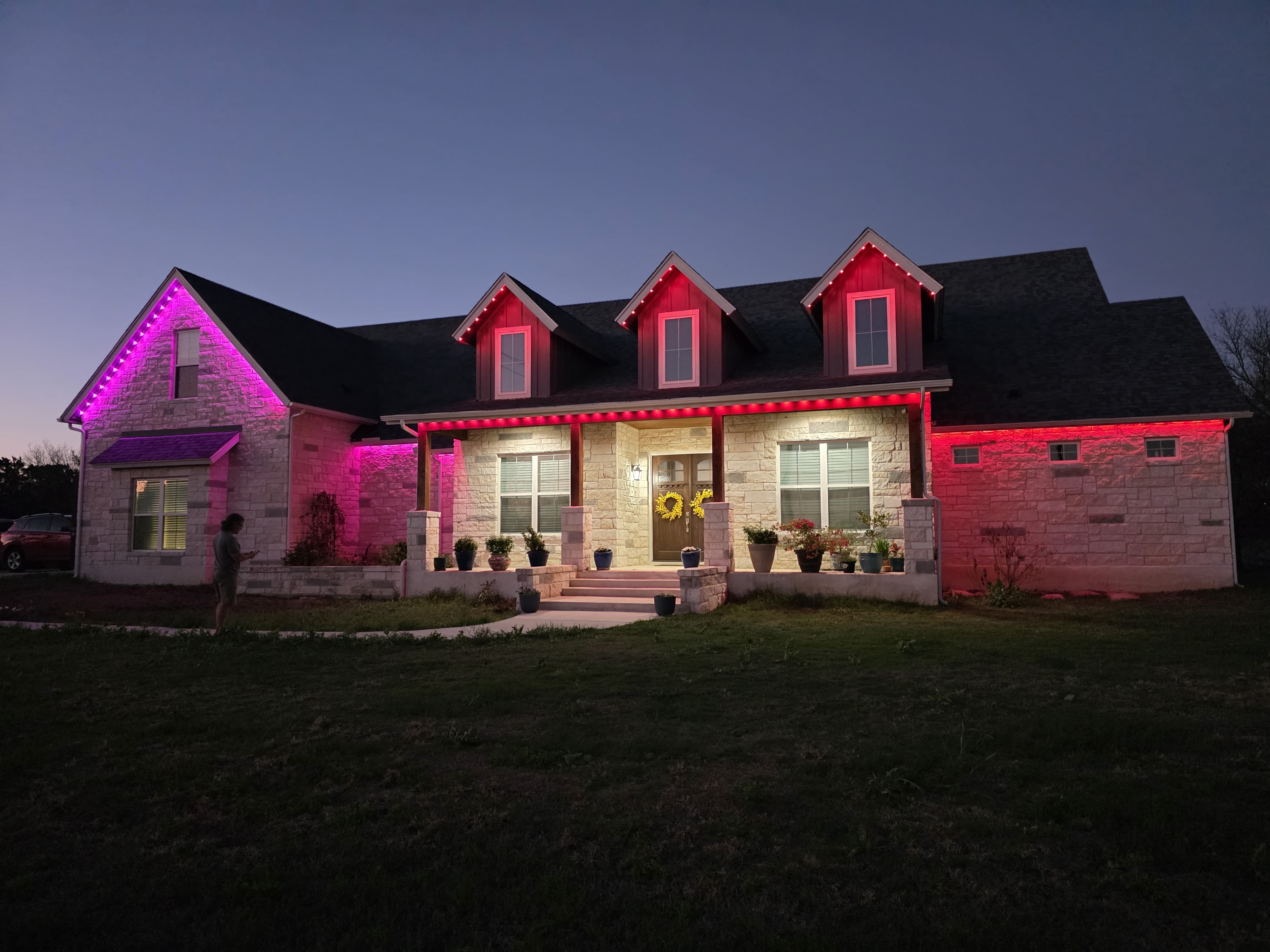 A single-story home lit in pink and red across the full roofline
