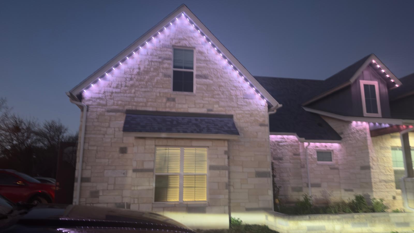 A Texas home at dusk with warm white permanent lighting running along the roofline
