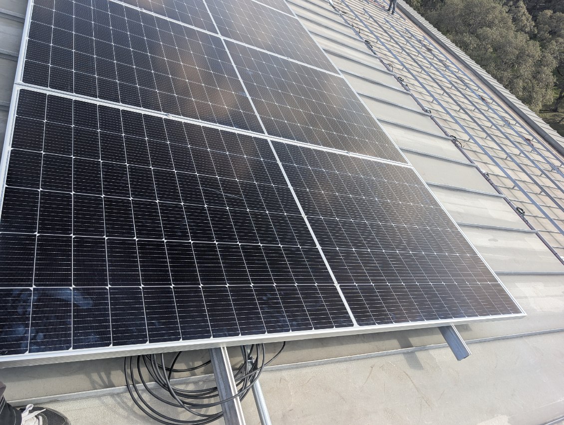 Close view of commercial solar panels, racking and DC cabling on a metal roof